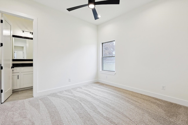 unfurnished bedroom with ceiling fan, light colored carpet, and ensuite bathroom