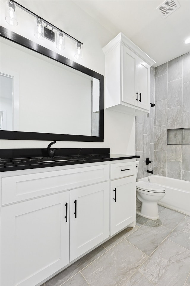 full bathroom featuring tiled shower / bath, vanity, and toilet