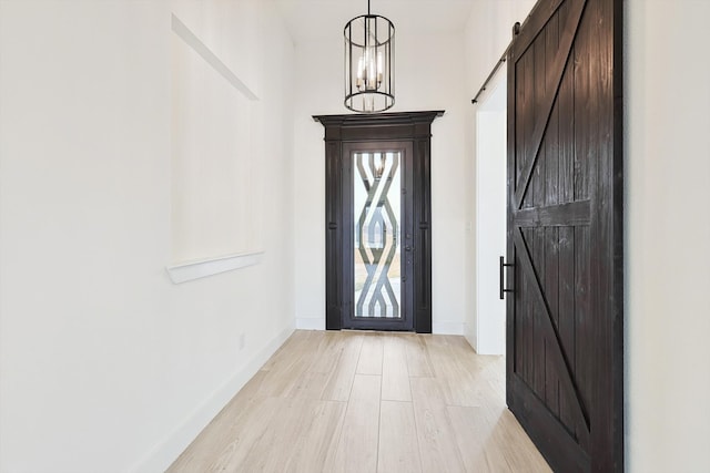 foyer featuring a chandelier, light hardwood / wood-style floors, and a barn door