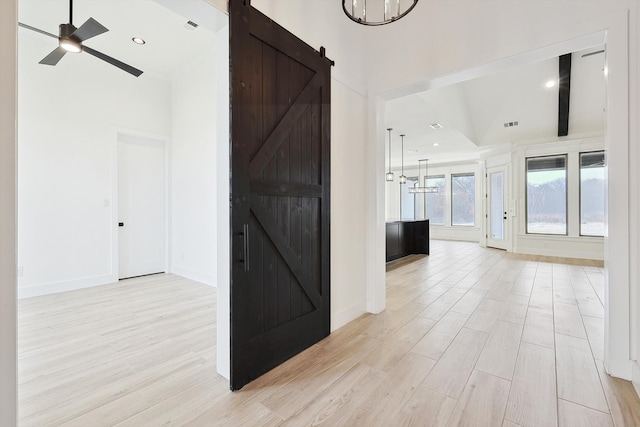 corridor featuring an inviting chandelier, light hardwood / wood-style floors, and a barn door