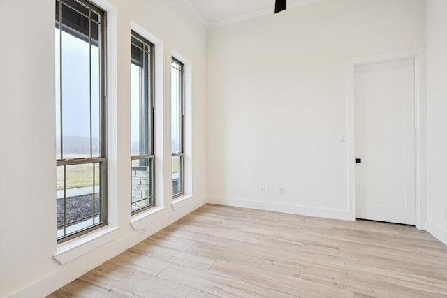 empty room with ornamental molding and light hardwood / wood-style floors