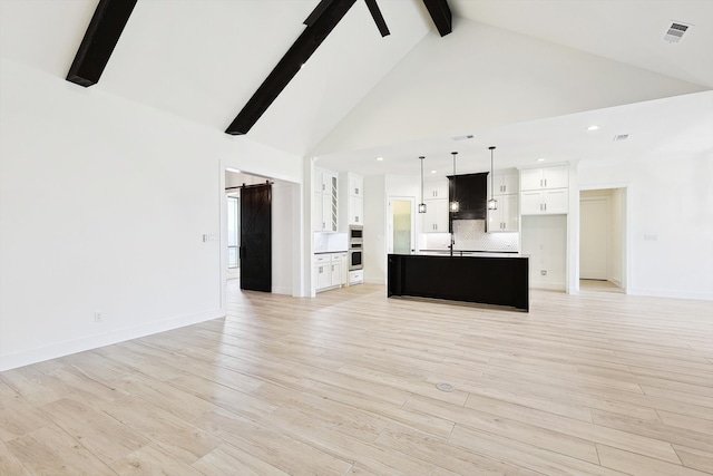 unfurnished living room featuring high vaulted ceiling, beam ceiling, light hardwood / wood-style floors, and sink