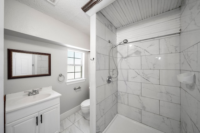 bathroom with a tile shower, vanity, and toilet