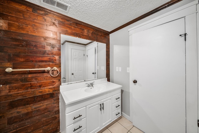 bathroom with vanity, a textured ceiling, ornamental molding, wooden walls, and tile patterned floors