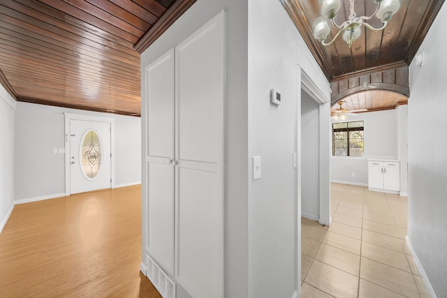 hallway with a notable chandelier, light tile patterned flooring, ornamental molding, and wooden ceiling