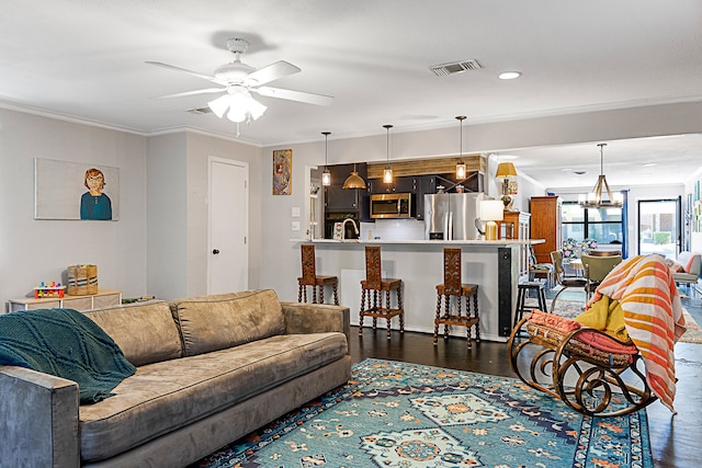 living room with ornamental molding, sink, ceiling fan with notable chandelier, and dark wood-type flooring