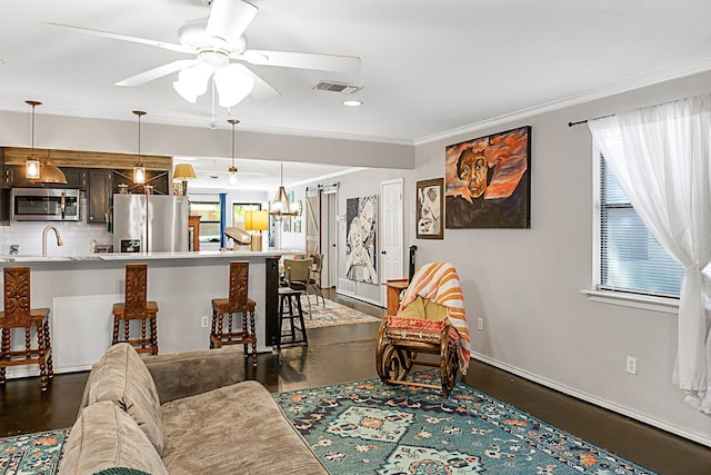 living room with sink, ceiling fan with notable chandelier, and ornamental molding