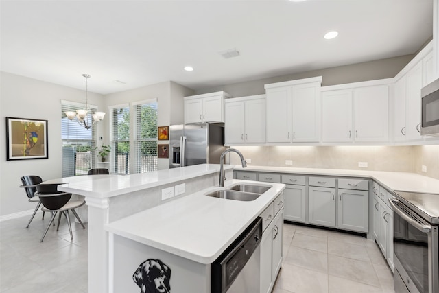 kitchen with sink, decorative light fixtures, a kitchen island with sink, stainless steel appliances, and an inviting chandelier