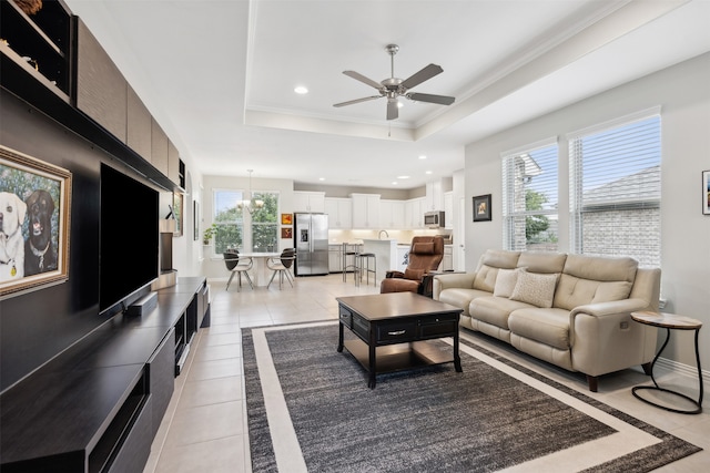 tiled living room featuring ceiling fan, a raised ceiling, plenty of natural light, and ornamental molding