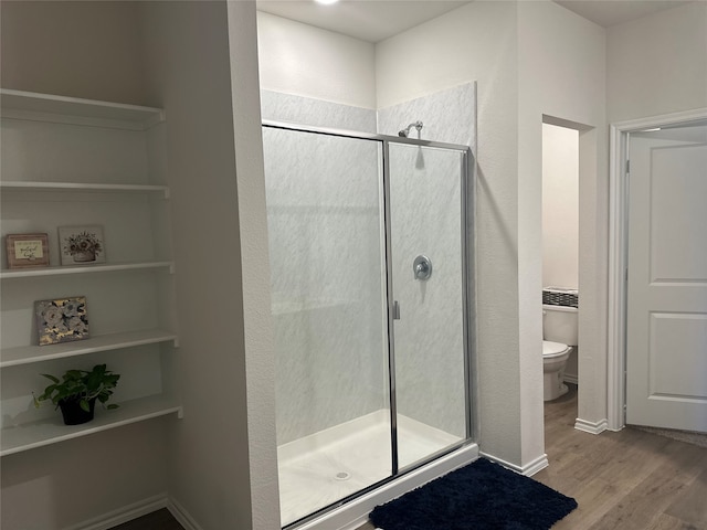 bathroom with a shower with door, hardwood / wood-style flooring, and toilet