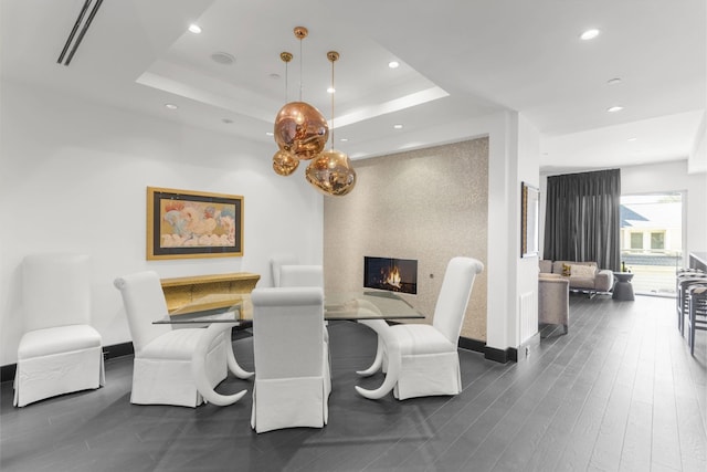 dining space with a tray ceiling and dark hardwood / wood-style floors