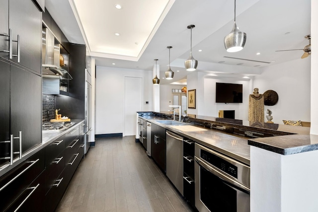 kitchen featuring sink, decorative light fixtures, backsplash, appliances with stainless steel finishes, and dark hardwood / wood-style floors