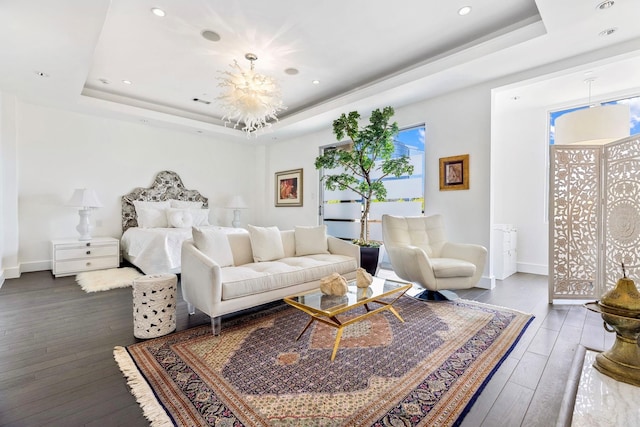 living room featuring a tray ceiling, a chandelier, and dark wood-type flooring