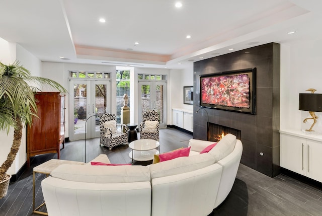 living room with dark hardwood / wood-style floors, a raised ceiling, a fireplace, and french doors