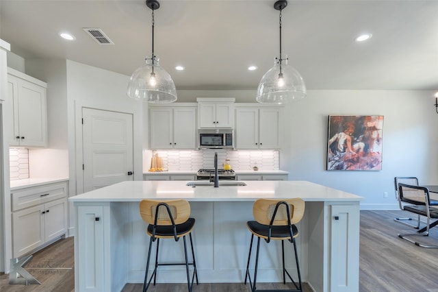 kitchen featuring dark wood-type flooring, stainless steel microwave, a sink, and visible vents