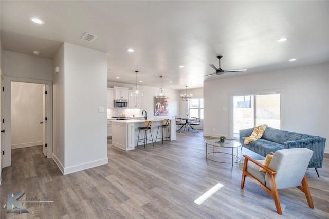 living room featuring light wood finished floors, baseboards, visible vents, and recessed lighting