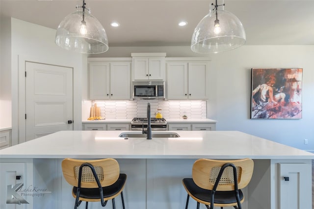 kitchen featuring light countertops, tasteful backsplash, stainless steel microwave, and a sink