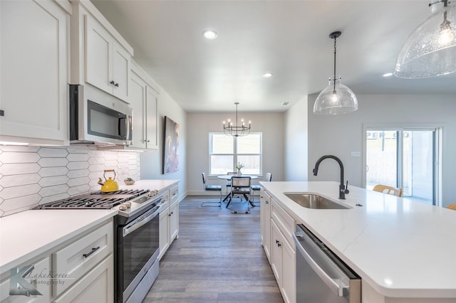 kitchen featuring a center island with sink, a sink, stainless steel appliances, light wood-style floors, and backsplash