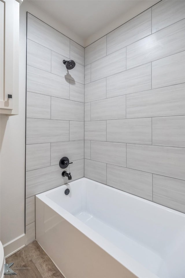 bathroom with toilet, tub / shower combination, and wood finished floors