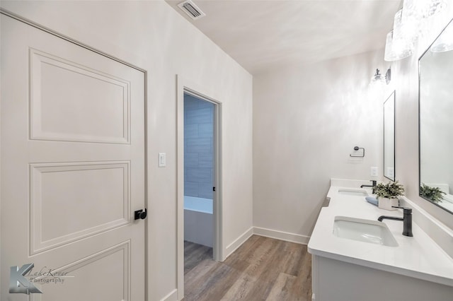 bathroom featuring baseboards, visible vents, a sink, and wood finished floors