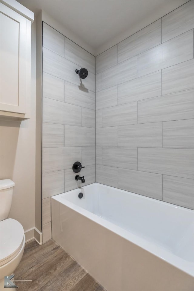 bathroom featuring  shower combination, baseboards, toilet, and wood finished floors