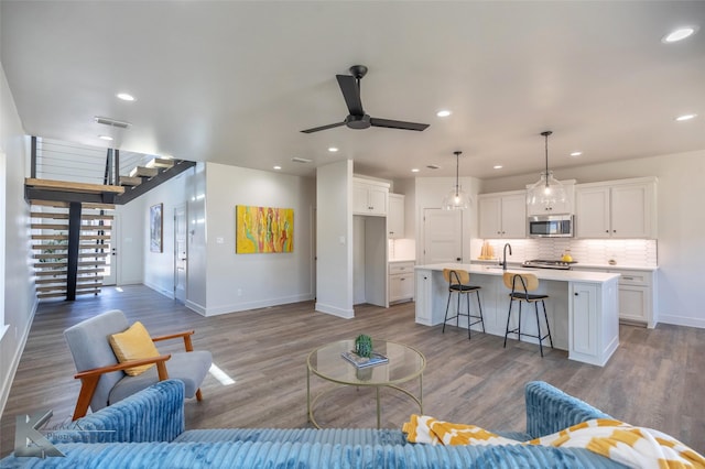 living area featuring stairway, recessed lighting, wood finished floors, and baseboards