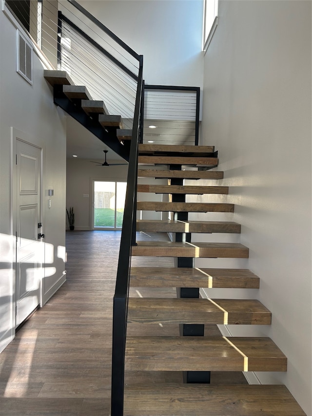 staircase with a towering ceiling and hardwood / wood-style flooring