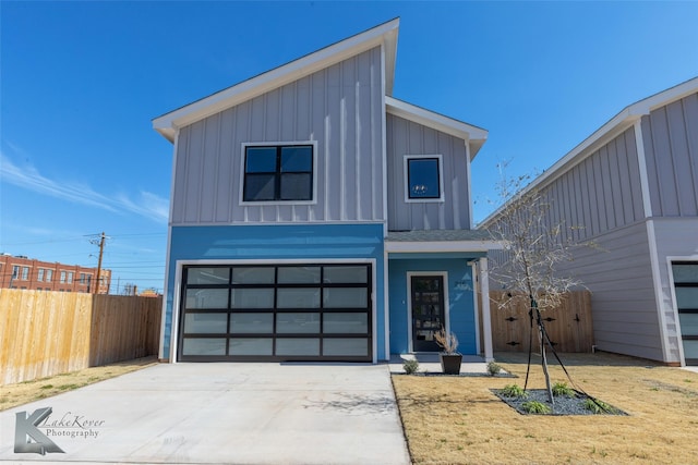 contemporary home with a garage, concrete driveway, board and batten siding, and fence