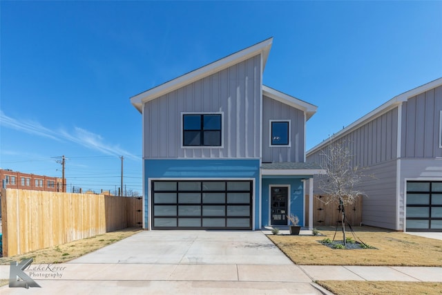 modern home with an attached garage, driveway, fence, and board and batten siding