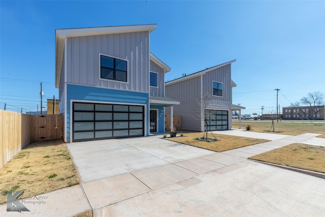 modern home featuring a garage, driveway, board and batten siding, and fence