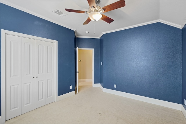 unfurnished bedroom featuring light carpet, ceiling fan, crown molding, a closet, and lofted ceiling