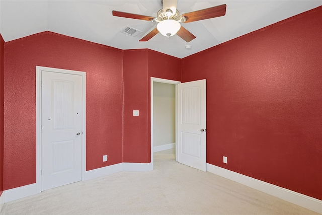 unfurnished bedroom featuring light colored carpet, vaulted ceiling, and ceiling fan