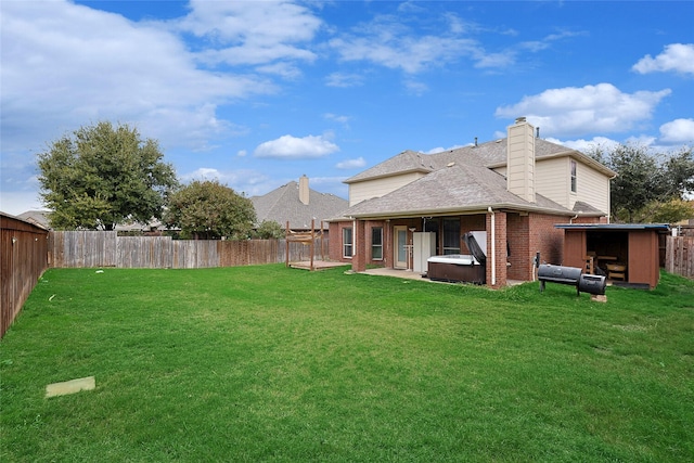 rear view of house with a yard and a hot tub