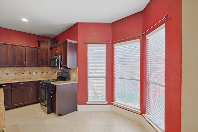 kitchen featuring dark brown cabinets, gas stove, tasteful backsplash, and light tile patterned flooring