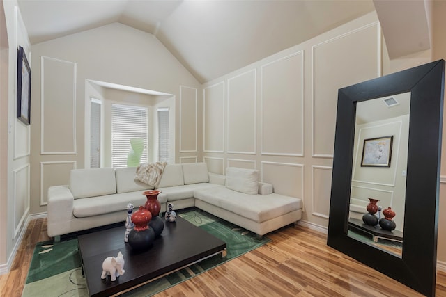 living room featuring wood-type flooring and vaulted ceiling