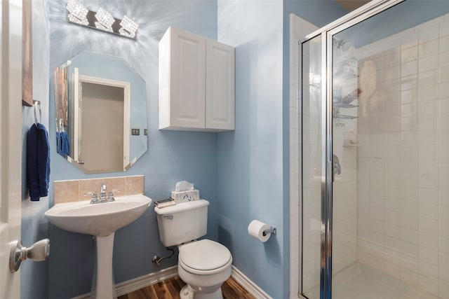 bathroom featuring wood-type flooring, a shower with door, and toilet