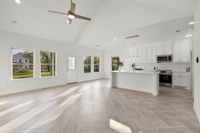 kitchen featuring hanging light fixtures, white cabinetry, a kitchen island with sink, high vaulted ceiling, and stainless steel appliances