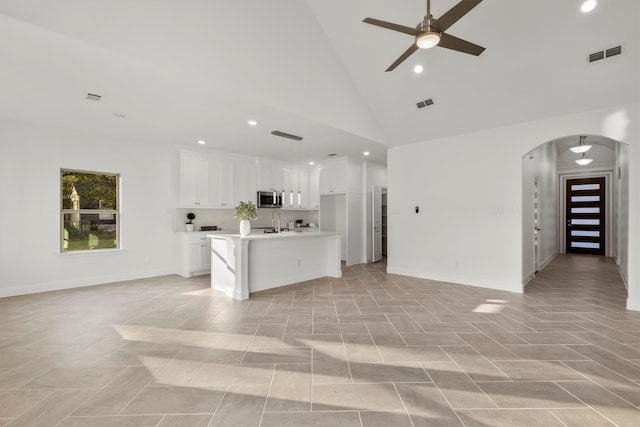 kitchen featuring an island with sink, sink, white cabinetry, high vaulted ceiling, and ceiling fan