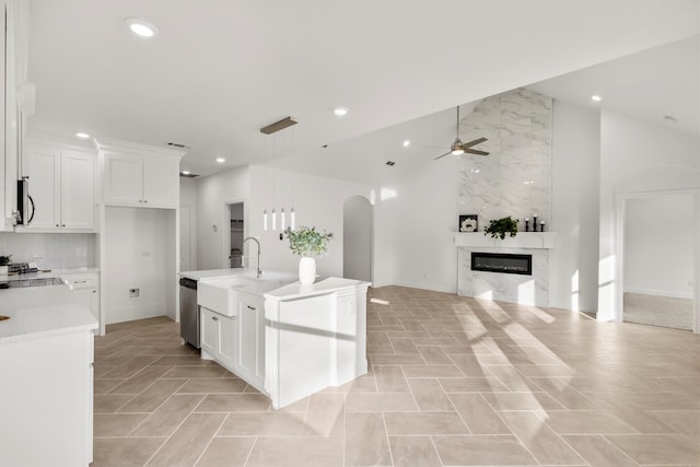 kitchen with a kitchen island with sink, a premium fireplace, sink, white cabinetry, and appliances with stainless steel finishes