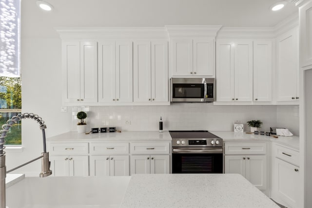 kitchen with decorative backsplash, white cabinets, light stone countertops, and stainless steel appliances