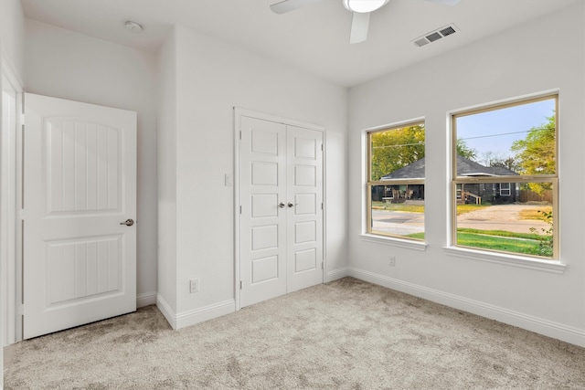 unfurnished bedroom featuring a closet, ceiling fan, and light colored carpet