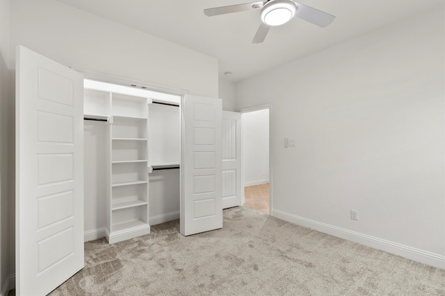 unfurnished bedroom with a closet, light colored carpet, and ceiling fan