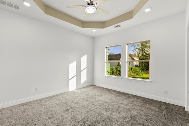 unfurnished room featuring ceiling fan, carpet flooring, and a raised ceiling