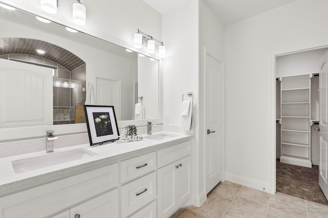 bathroom with vanity, a tile shower, and tile patterned floors