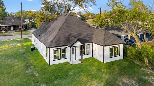 rear view of property featuring a yard and central AC