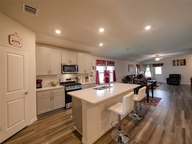 kitchen featuring appliances with stainless steel finishes, a kitchen breakfast bar, a kitchen island with sink, dark wood-type flooring, and sink