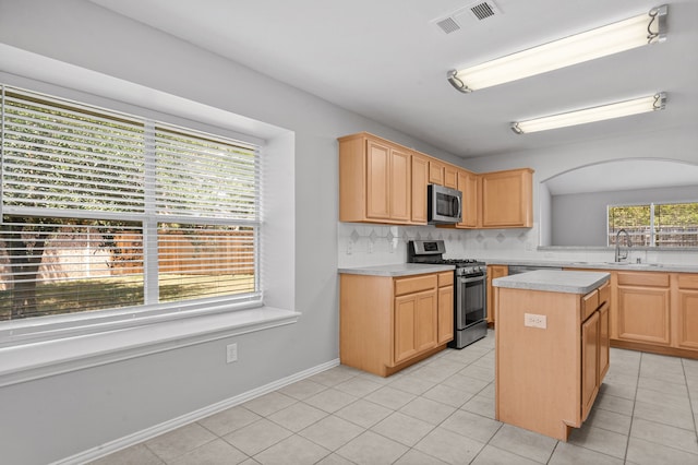 kitchen featuring a center island, tasteful backsplash, sink, appliances with stainless steel finishes, and light brown cabinetry