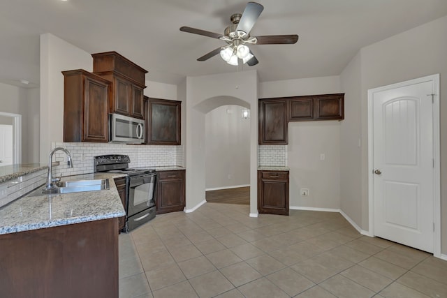 kitchen with light stone counters, backsplash, ceiling fan, sink, and electric range