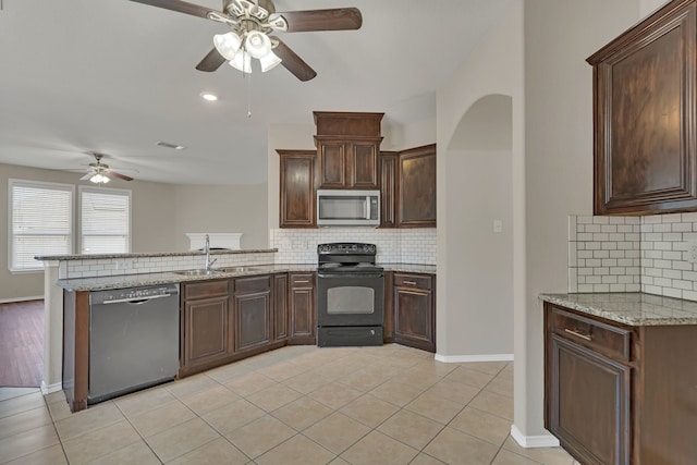 kitchen featuring kitchen peninsula, light stone countertops, stainless steel appliances, ceiling fan, and sink