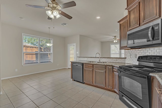 kitchen with ceiling fan, light stone countertops, appliances with stainless steel finishes, and sink